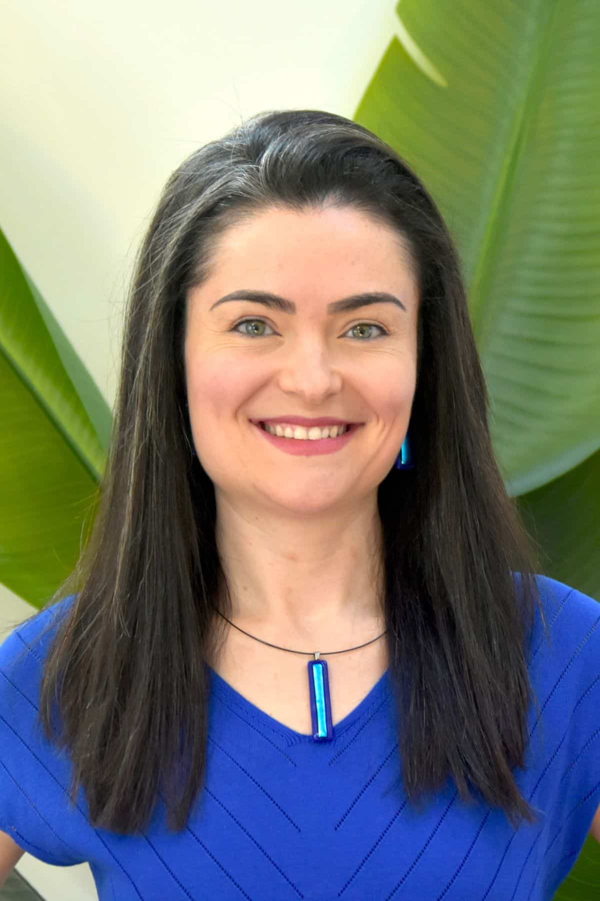 Life coach seated at a desk using a laptop, smiling gently during an online session.