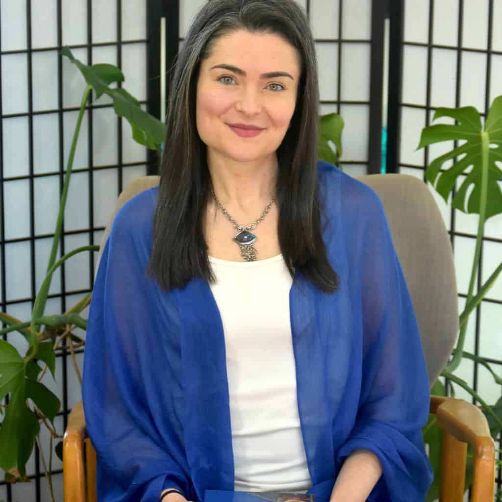 Resilience coach Mary Simon seated indoors, smiling warmly in a calm, welcoming setting.