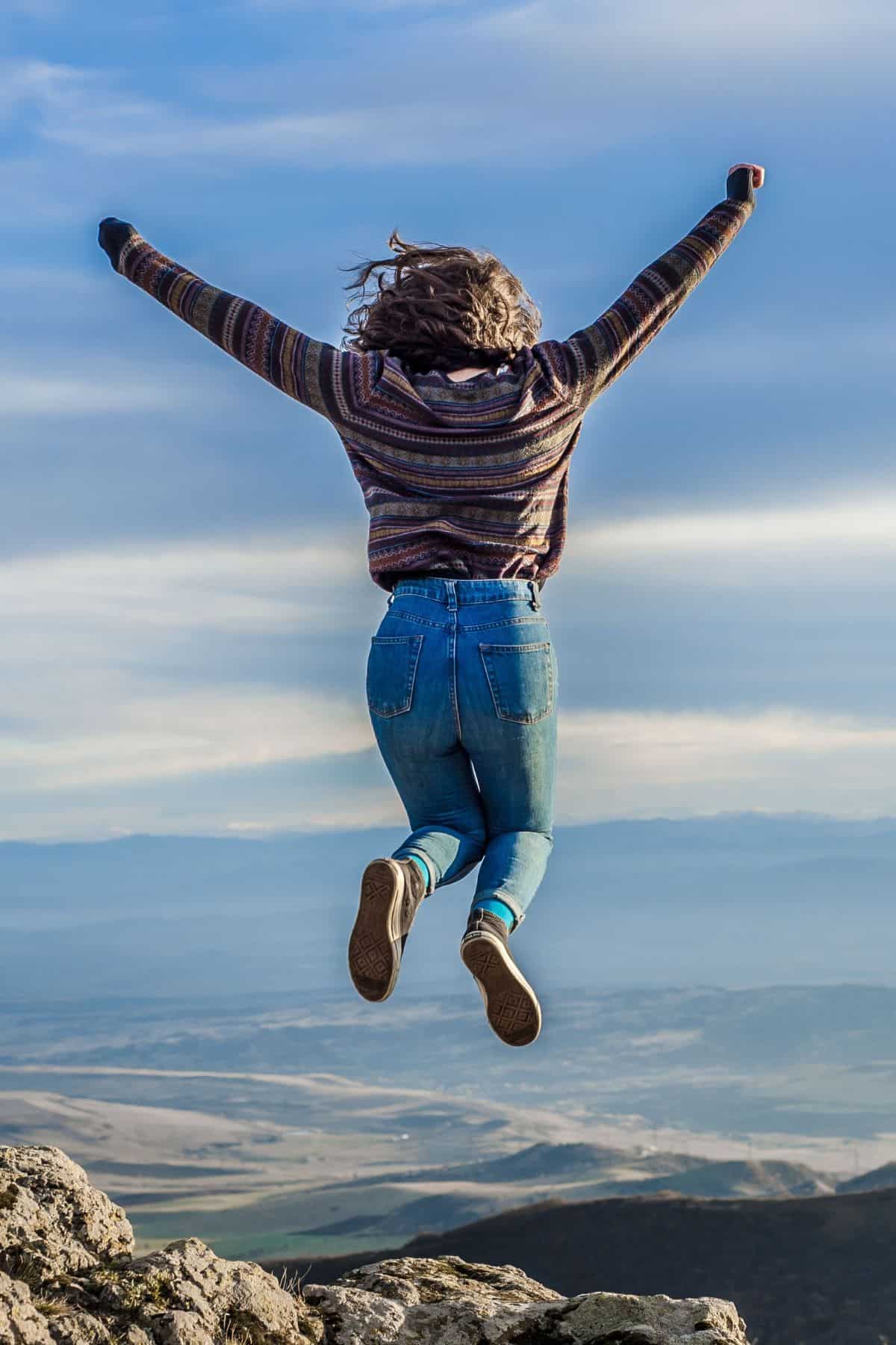 A girl jump up on a mountain